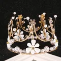 Elegant gold metal cake crown topper with white flowers and pearls on dark background - Queen Flower Crown