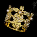 Dettaglio di corona dorata con perle bianche e cristalli su sfondo nero - Oro