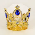 Detailed view of a golden tiara featuring a large blue teardrop gemstone and white rhinestones - Gold + Blue