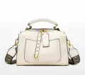 Detail der weißen Handtasche mit Webstruktur, Goldnieten und geometrischem Gurtband - Weiß