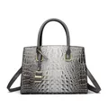 Gray crocodile texture handbag with gold hardware and shoulder strap on white background - Gray