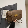 Vintage brown leather crossbody bag with gold buckle and adjustable strap on suit - Oak Camel