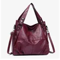 Detalle de bolso bandolera burdeos con textura de cuero granulado y costuras cruzadas - Rojo