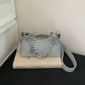 Chic light blue crescent underarm bag with silver chain strap on a vintage book - Light Blue