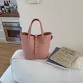 Pink lychee grain bucket bag with dual handles shown on a white sofa backdrop - Without Pendant / Pink