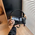 Glossy black cylindrical handbag with gold hardware and leopard heart charm - Black With Pendant