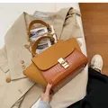 Details der mattierten Handtasche in Ingwergelb mit Krokostruktur und Goldverschluss - Braun