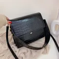 Zwarte crossbody tas met krokodillenprint en gouden details op gebreide achtergrond - Zwart