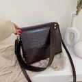 Donkerbruine crossbody tas met krokodillenprint en gouden gesp met brede schouderriem - koffiekleur