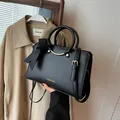 Black bucket bag with gold lettering, circular handles and a decorative side bow tie - Black