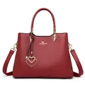 Elegant wine red lychee leather handbag with golden hardware and double heart charm pendant - Burgundy
