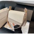 Detail of beige quilted shoulder bag with gold clasp shown with premium gift packaging - Off White