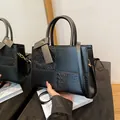 Structured black handbag featuring crocodile texture panels and gold-tone metal hardware - Black