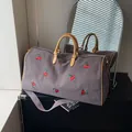 Sac de voyage en toile gris foncé avec broderie cerise et poignées jaunes contrastées - café