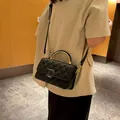 Schicke schwarze Stepptasche mit goldener D-Schnalle und Griff an einem Model - Schwarz