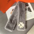 Detalle de bufanda gris de piel sintética con motivo de trébol blanco sobre una revista - Gris