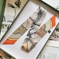 Detail eines Seidenschals mit Reitsport-Druck in einer Vintage-Geschenkbox für Damen - Orange