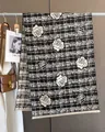 Detail of black and white plaid scarf featuring white rose patterns and fringe edges - Black