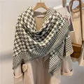 Detalle de bufanda gris de pata de gallo con flecos colgada en percha de madera - 130x130cm / Gris