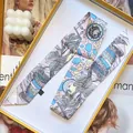 Macro detail of silk skinny scarf with floral print and washing label on handle wrap - 5cmx90cm / Nude Pink