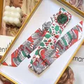 Makroaufnahme eines Twilly-Seidenschals mit tropischem Print in einer Geschenkbox - 5cmx90cm / Grün