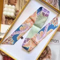 Detailed view of long colorful giraffe print twilly scarf folded in a gift box - Purple