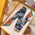 Detailopname van de luxe zijden twilly sjaal met bloemenprint in oranje geschenkdoos - Saffierblauw