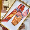 Close-up of a colorful patterned silk twilly ribbon with geometric prints in a gift box - Orange
