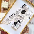 Elegante zijdeachtige twilly sjaal met zwart camelia bloemenpatroon op crèmewitte basis - Beige