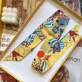 Dettaglio del foulard twilly in seta gialla con stampa pop-art in confezione regalo - Giallo