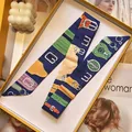 Close-up of luxury navy printed silk twilly scarf neatly folded in a yellow gift box - Navy Blue Equestrian Style (S1860-5)