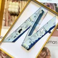 Macro view of blue silk twilly scarf with dog patterns in a decorative gift box - Light Blue