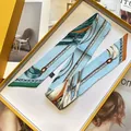 Detail eines hellblauen Seiden-Twilly mit nautischen Mustern in gelber Geschenkbox - Langes Band / Blau