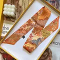 Detail of premium silk scarf with zebra floral print inside a yellow luxury gift box - 5x90cm / Orange