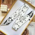 Detail view of panda pattern silk scarf folded in a gift box with a care label - Panda (S291)