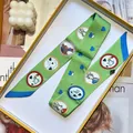 Green silk skinny scarf with equestrian illustrations in a yellow gift box - Green