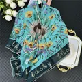Close-up of floral silk scarf with Lucky lettering and vibrant sunflower pattern - Color 1 (Tiffany Blue/Sunflower)