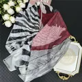 Detail of silk scarf with zebra and feather patterns on a stylish vanity setup - 130x130cm / Color 4 (Red Black White Feather Zebra)