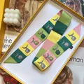 Macro detail of bird print satin ribbon scarf and yellow gift box on fashion magazine - Yellow