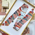 Narrow silk twilly scarf with geometric buckle print elegantly placed in a gift box - Red