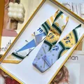 Narrow silk scarf with yellow geometric patterns displayed in an elegant gift box - Yellow