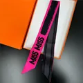 Gros plan d'un foulard en soie rose et noir avec imprimé MISS MISS dans sa boîte - Rose Rouge