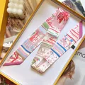 Pink and white patterned silk twilly scarf neatly displayed in a vibrant yellow gift box - Pink