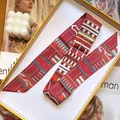 Detail of red geometric silk twilly scarf neatly displayed in an orange luxury gift box - Red