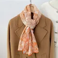 Detail of vintage floral print scarf paired with a wool coat on a wooden hanger - 160x33cm / Orange