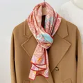 Detailed close-up of a floral print silk scarf styled on a classic wool coat - 160x33cm / Fuschia