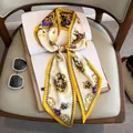 Eleganter goldener Seidenschal mit königlichem Wappen auf einem Buch für Herbstmode - Gold
