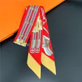 Detail of red silk twilly scarf with golden buckle print on iconic orange background - 11