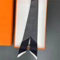 Dettaglio della sciarpa in seta a righe zebra in una confezione regalo arancione - Nero