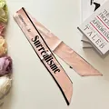 Detail of a pink silk scarf with black French lettering and delicate floral accents - Light Pink